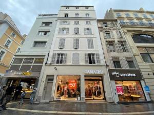 ein hohes weißes Gebäude in einer Stadtstraße mit einem Geschäft in der Unterkunft Studio Saint Ferreol hyper centre 3-1 in Marseille