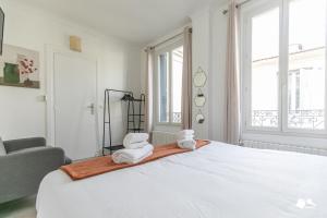 um quarto branco com uma cama grande e toalhas em MBA - Splendide Appart - Bobillot - Proche Vincennes em Montreuil