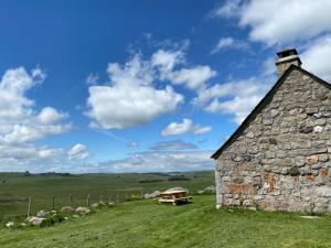 um antigo edifício de pedra com uma mesa de piquenique num campo em Buron Cœur d’Aubrac em Marchastel