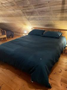 uma grande cama azul num quarto com tecto de madeira em Buron Cœur d’Aubrac em Marchastel