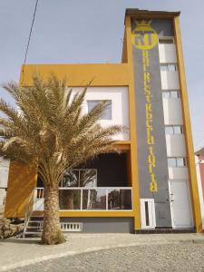 un edificio con una palmera delante de él en Residencial Ribeira Torta, en Porto Novo