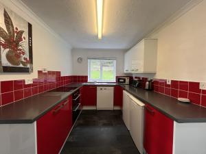 una cocina roja y blanca con azulejos rojos en The Lodge, en Lochgilphead