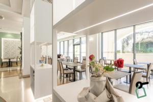 a dining room with tables and chairs and windows at HOTIDAY Hotel Otranto in Otranto