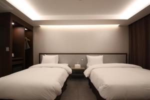 2 łóżka w pokoju hotelowym z białą pościelą w obiekcie Hotel J's w mieście Gumi