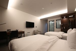 龜尾的住宿－Hotel J's，酒店客房设有两张床、一张桌子和一台电视。