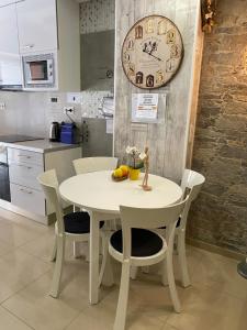 une table et des chaises blanches dans une cuisine avec une horloge dans l'établissement BADAROSA 2 House10min to BARCELONCity&NearTo BEACH, à Badalona