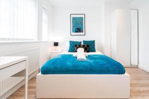 una camera da letto con un grande letto blu in una stanza bianca di 4 Bedroom House - Parking & Garden - Smart TVs - Netflix - Wifi - 22CG a Birmingham
