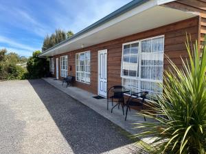 a house with a table and chairs on the porch at Castaway Holiday Apartments in Strahan