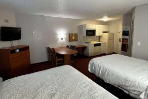 a hotel room with two beds and a table and a kitchen at Days Inn & Suites by Wyndham Green Bay WI in Green Bay