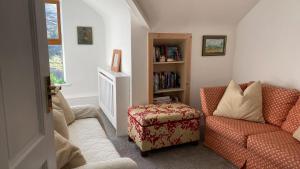 a living room with a chair and a book shelf at Drop Anchor House, Spacious 3 bedroom apartment, fabulous sea views in Cleggan