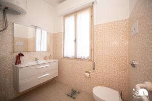uma casa de banho com um lavatório, um WC e uma janela. em Villa Torchio em Manerba del Garda