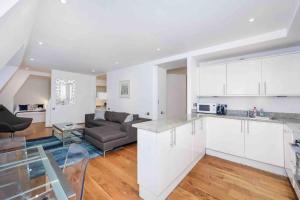 cocina y sala de estar con armarios blancos y sofá en Oxford Circus Station Apartment- Mayfair! en Londres