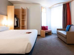 a hotel room with a bed and a chair at ibis Paris Opera La Fayette in Paris