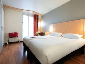 a large white bed in a room with a window at ibis Paris Opera La Fayette in Paris