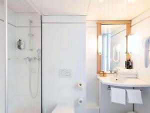 baño blanco con ducha y lavamanos en ibis Paris Opera La Fayette, en París