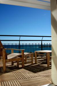 a picnic table and benches on a pier with the ocean at Hotel Napoléon in Menton
