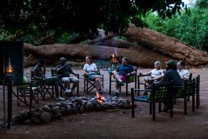 a group of people sitting around a fire at Nkula Camp - Pafuri Walking Safari's in Makuleke Contract Park