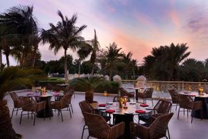 拉斯海瑪的住宿－哈伊馬角華爾道夫酒店，一个带桌椅的庭院,享有日落美景