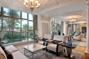 ein Wohnzimmer mit Stühlen, Tischen und Fenstern in der Unterkunft Waldorf Astoria Ras Al Khaimah in Ras al Khaimah