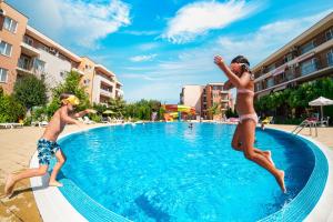 a couple of people jumping into a swimming pool at Holiday Garden Resort in Sunny Beach