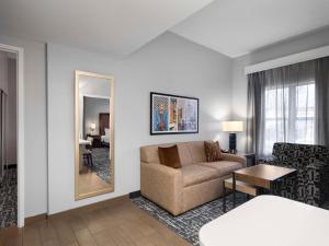 a living room with a couch and a mirror at Homewood Suites Columbus - Airport in Columbus