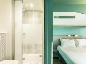a bedroom with a bed and a glass door at ibis budget Bourges in Bourges