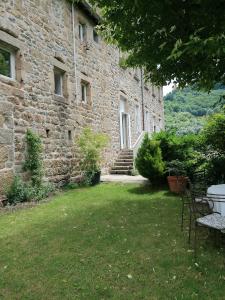 a stone building with a table and chairs in a yard at MARIAC , Chambres d'hôtes "AU TILLEUL" 6km du Cheylard in Mariac