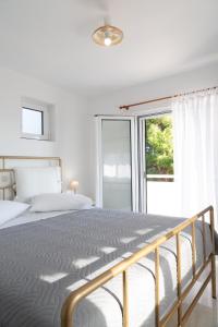 a white bedroom with a large bed and a window at Kineta Seaside Summer Apartments in Kineta