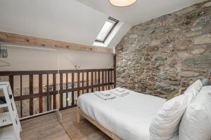 Zimmer mit einem Bett und einer Steinmauer in der Unterkunft Cheerful 2 bedroom cottage with garden in Llanelltyd