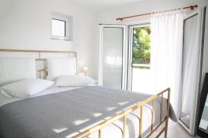 ein Schlafzimmer mit einem Bett und einem großen Fenster in der Unterkunft Kineta Seaside Summer Apartments in Kineta