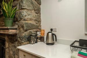 eine Küche mit einer Theke und einer Steinmauer in der Unterkunft Cheerful 2 bedroom cottage with garden in Llanelltyd