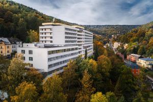a tall white building in the middle of a city at Hotel Běhounek in Jáchymov