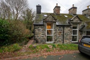 an old stone house with a car parked in front at Cheerful 2 bedroom cottage with garden in Llanelltyd