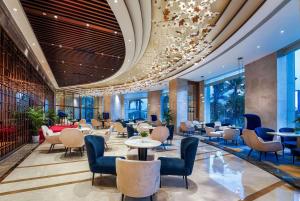 een lobby van een hotel met tafels en stoelen bij Howard Johnson by Wyndham Huaqiao Plaza Xinyu in Xinyu