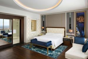 Grand Hyatt Al Khobar Hotel and Residences في الخبر: غرفة نوم بسرير وكرسي وأريكة