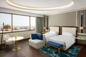 Grand Hyatt Al Khobar Hotel and Residences في الخبر: غرفة فندقية بسرير وطاولة وكراسي