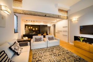 TA - One bedroom luxury apartment in the fashion district في فلورنسا: غرفة معيشة بها كنبتين بيضاء ومطبخ