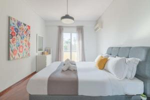 a bedroom with a large white bed with stuffed animals on it at The HostMaster Beachside Retreat in Vari