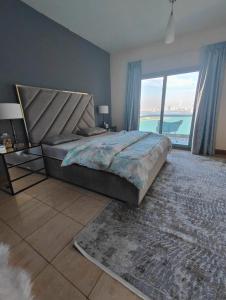 a bedroom with a large bed and a large window at Luxury Corniche Apartment in Sharjah