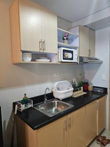 eine Küche mit einer Spüle und einer Mikrowelle in der Unterkunft The Metro Haven in Manila