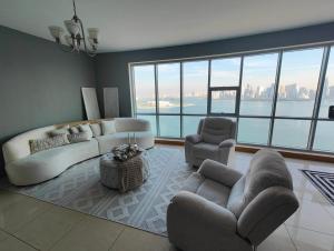 a living room with a couch and chairs and a large window at Luxury Corniche Apartment in Sharjah