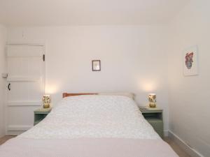 a bedroom with a bed with two nightstands and two lamps at Bluebird Cottage in Castle Cary