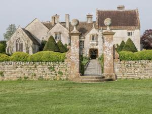 ein altes Haus mit einer Steinmauer und einem Tor in der Unterkunft Bluebird Cottage in Castle Cary