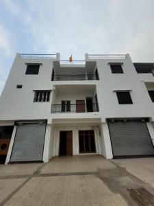 a white building with two garage doors and windows at Pushpa Vatika in Faizābād