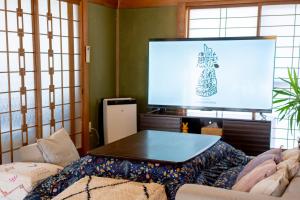 a living room with a tv and a table at Shachihoko 海辺の一棟貸切ヴィラ しゃちほこ in Imari