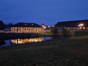 a building with a reflection in a pond at night at Dworek Hołny in Hołny Mejera