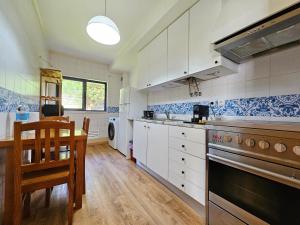 a kitchen with white cabinets and a table and a stove at Sweet Blue Home in Ponta Delgada