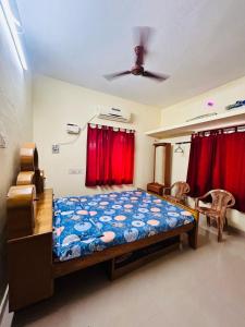 a bedroom with a bed and red curtains at Sirvachur madhurakalli amman guest house in Perambalūr