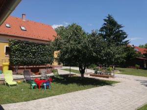 um grupo de cadeiras e uma árvore num quintal em Ferenc Vendégháza em Balatonlelle