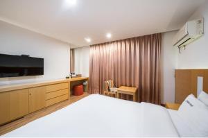 um quarto de hotel com uma cama e uma televisão de ecrã plano em Wate Hotel em Yeosu